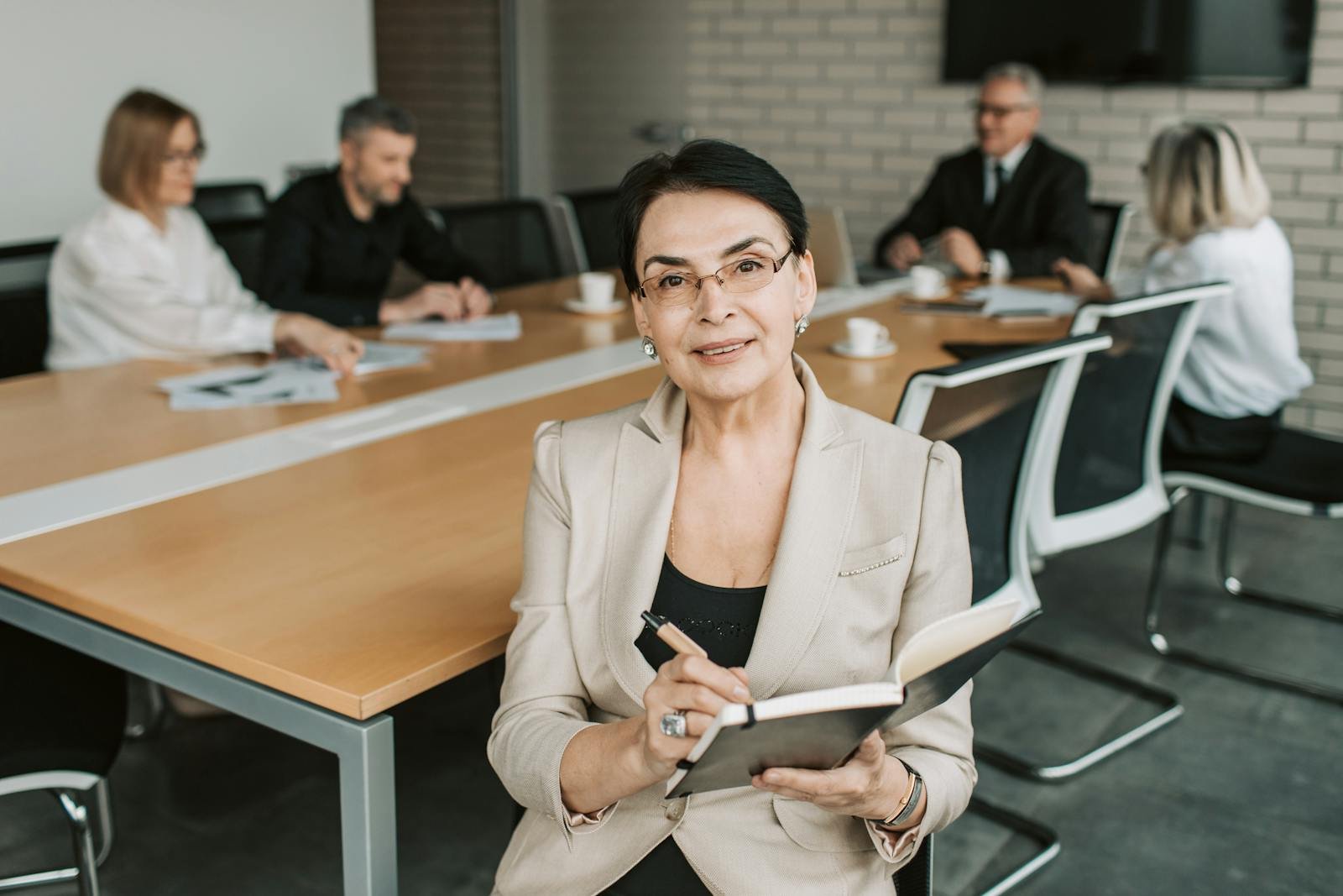 Senior businesswoman leading a meeting with colleagues in a modern office space.