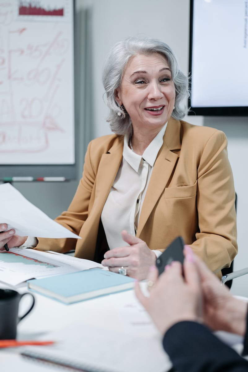 Confident senior businesswoman leads a meeting with colleagues in a modern office setting.